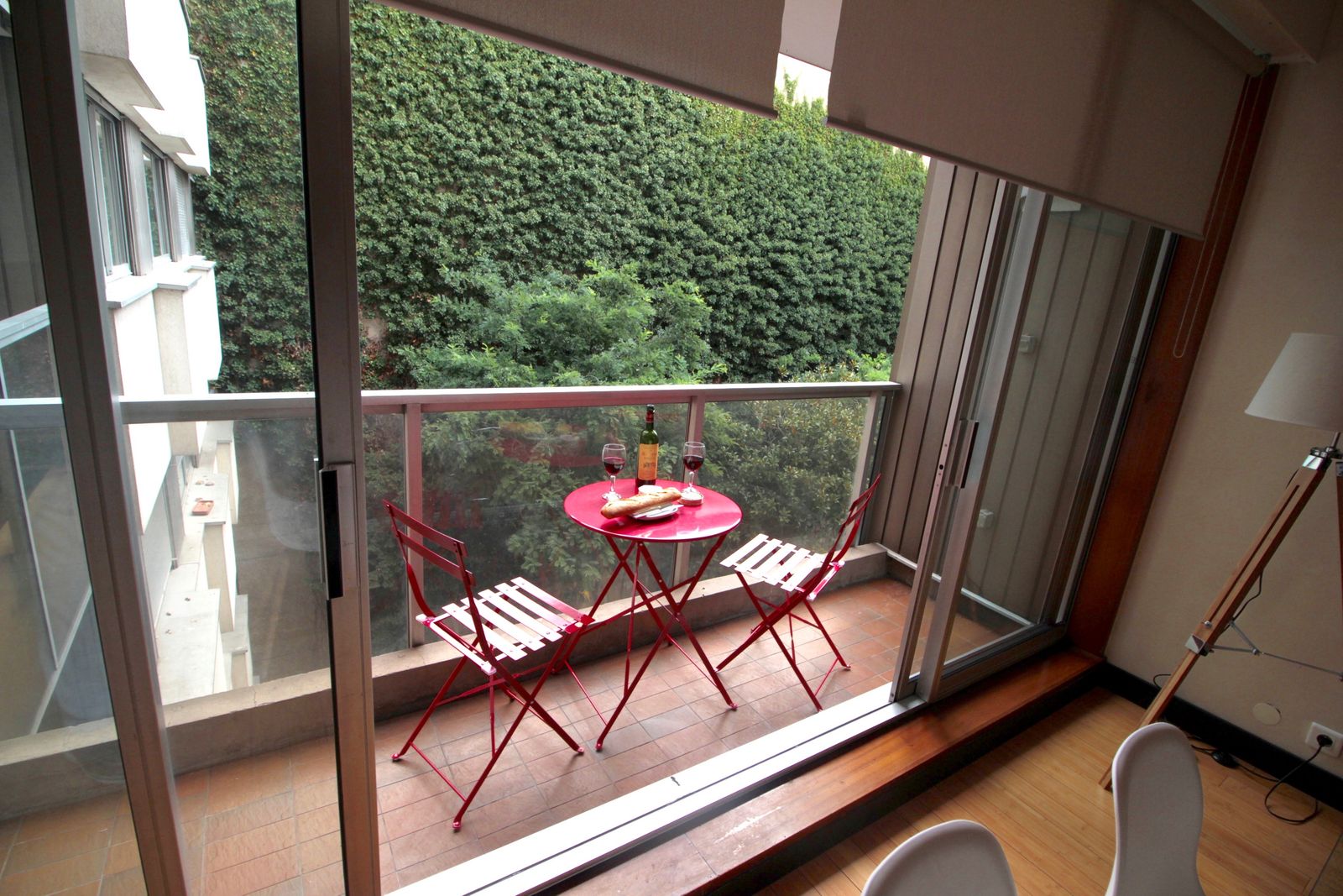 Charming balcony with red bistro table and chairs surrounded by green ivy at Short Stay Paris 2nd floor apartment
