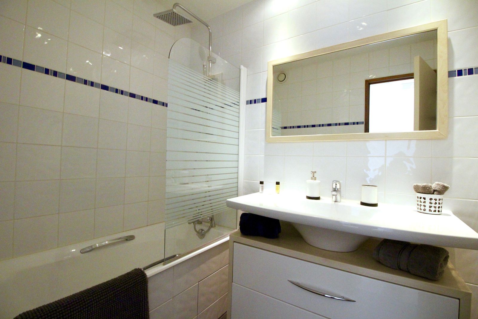 Modern bathroom with bathtub and shower combination, vanity unit, and decorative blue tiling