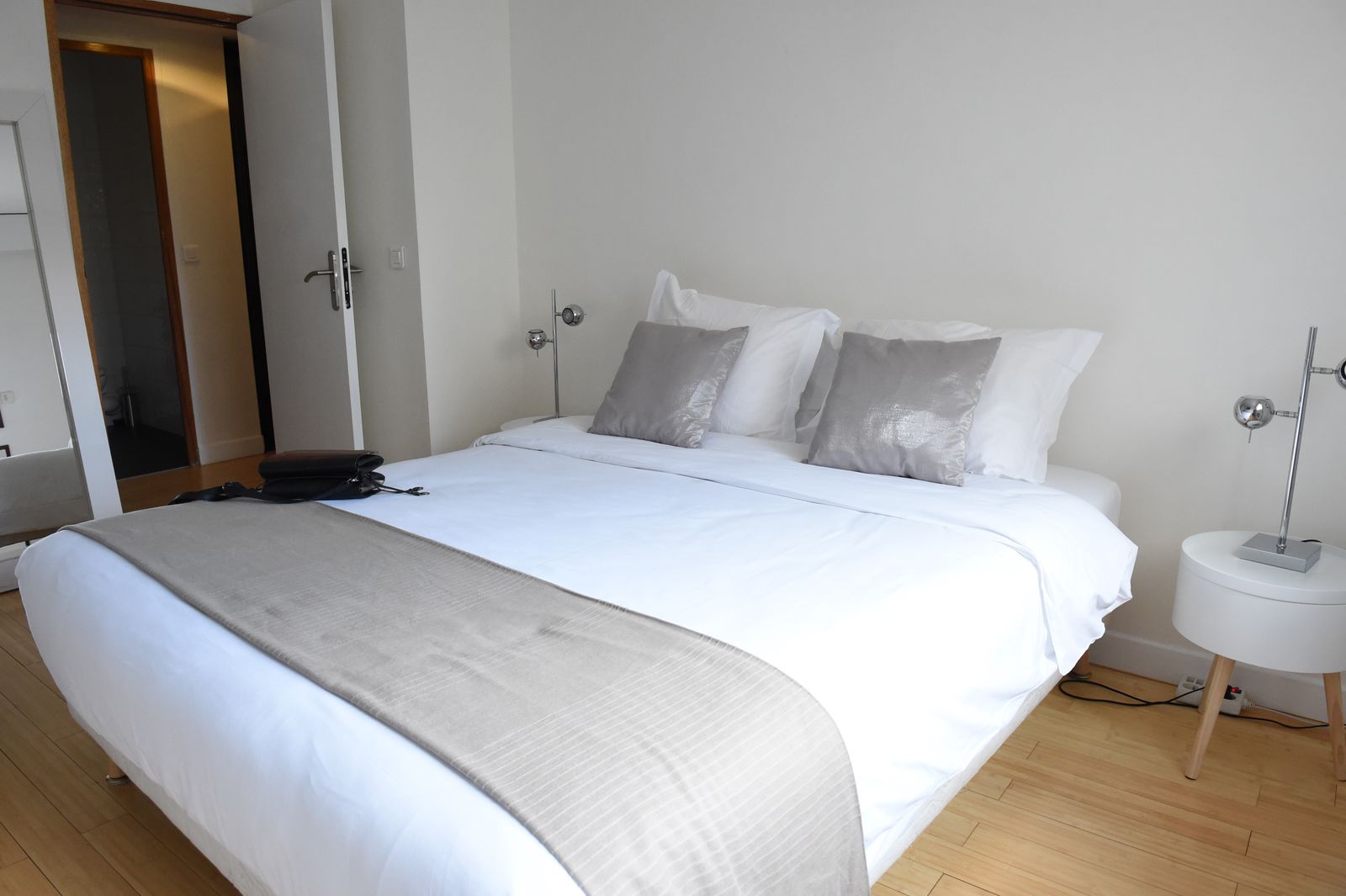 Lit double avec coussins gris et lampe de chevet