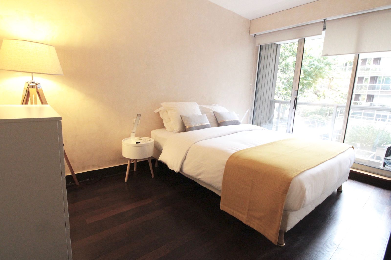 Comfortable bedroom with double bed, yellow throw blanket, bedside lamp, and balcony access