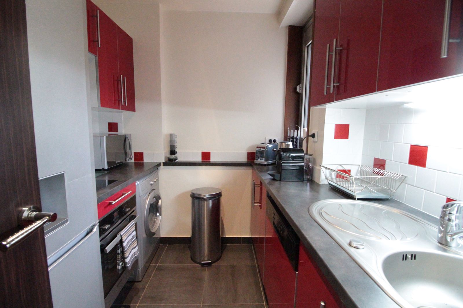 Cuisine rouge avec plan de travail sombre et lave-linge
